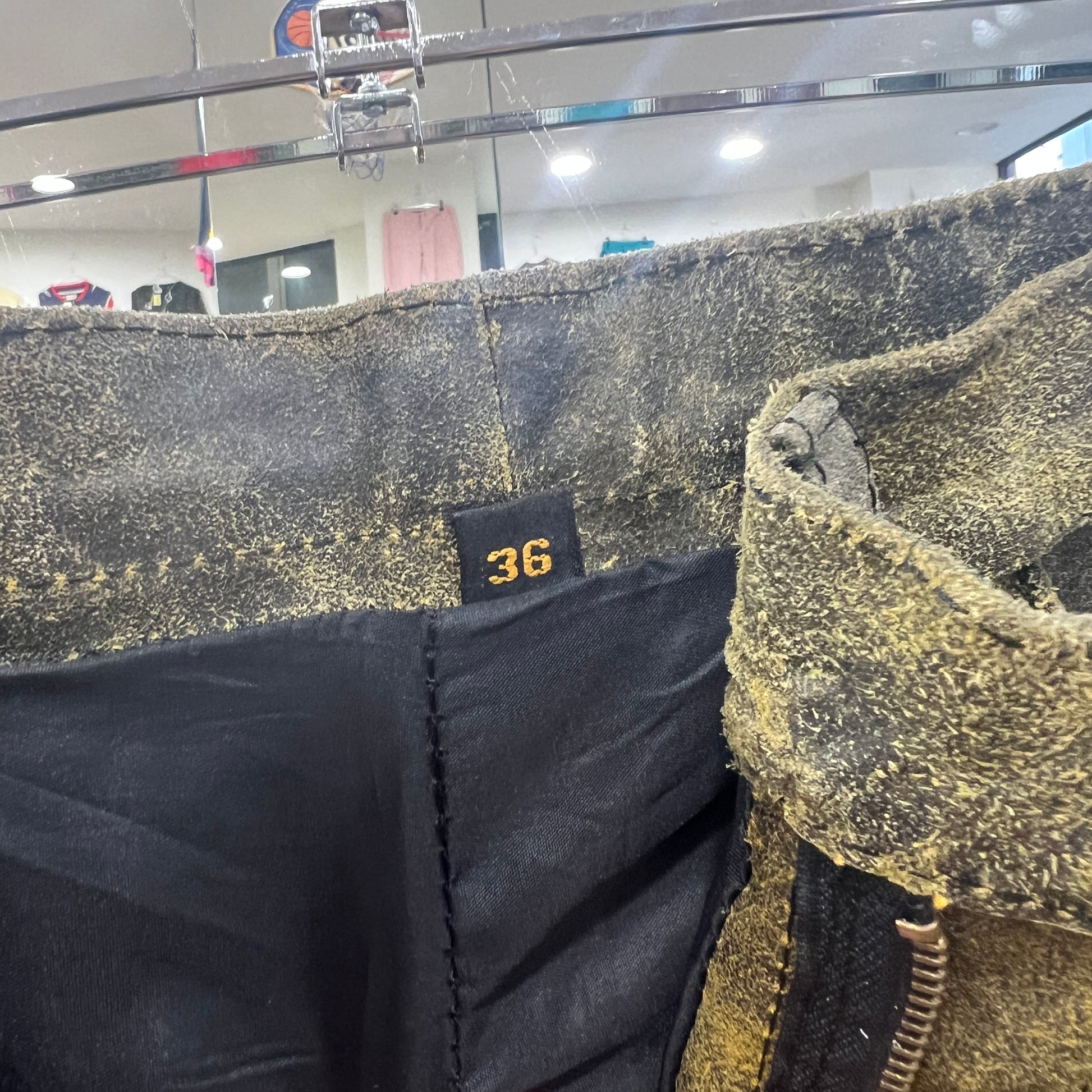 Close-up of  leather pants with a visible brand tag in a store setting