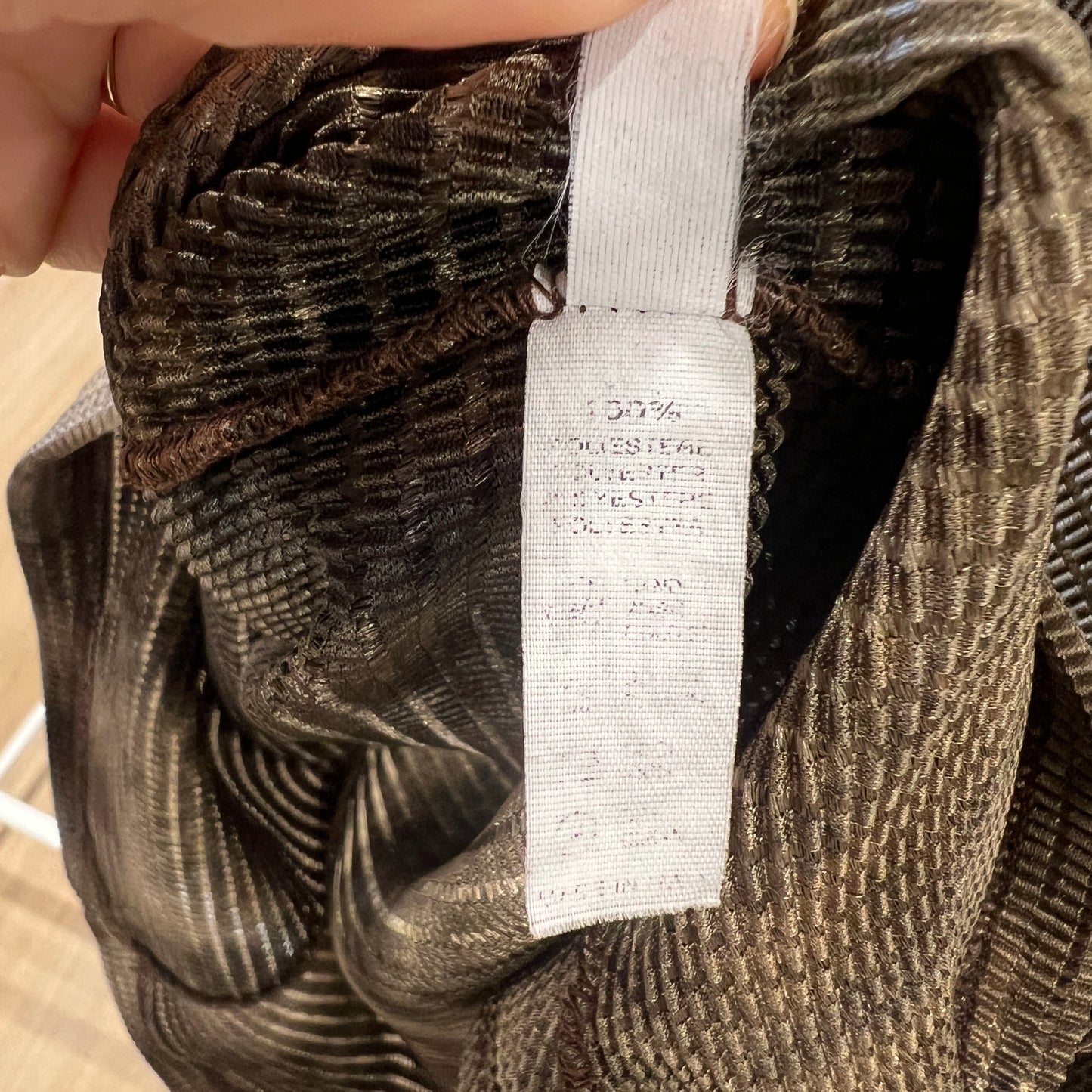 Close-up of a textured fabric with a visible label, held by a hand