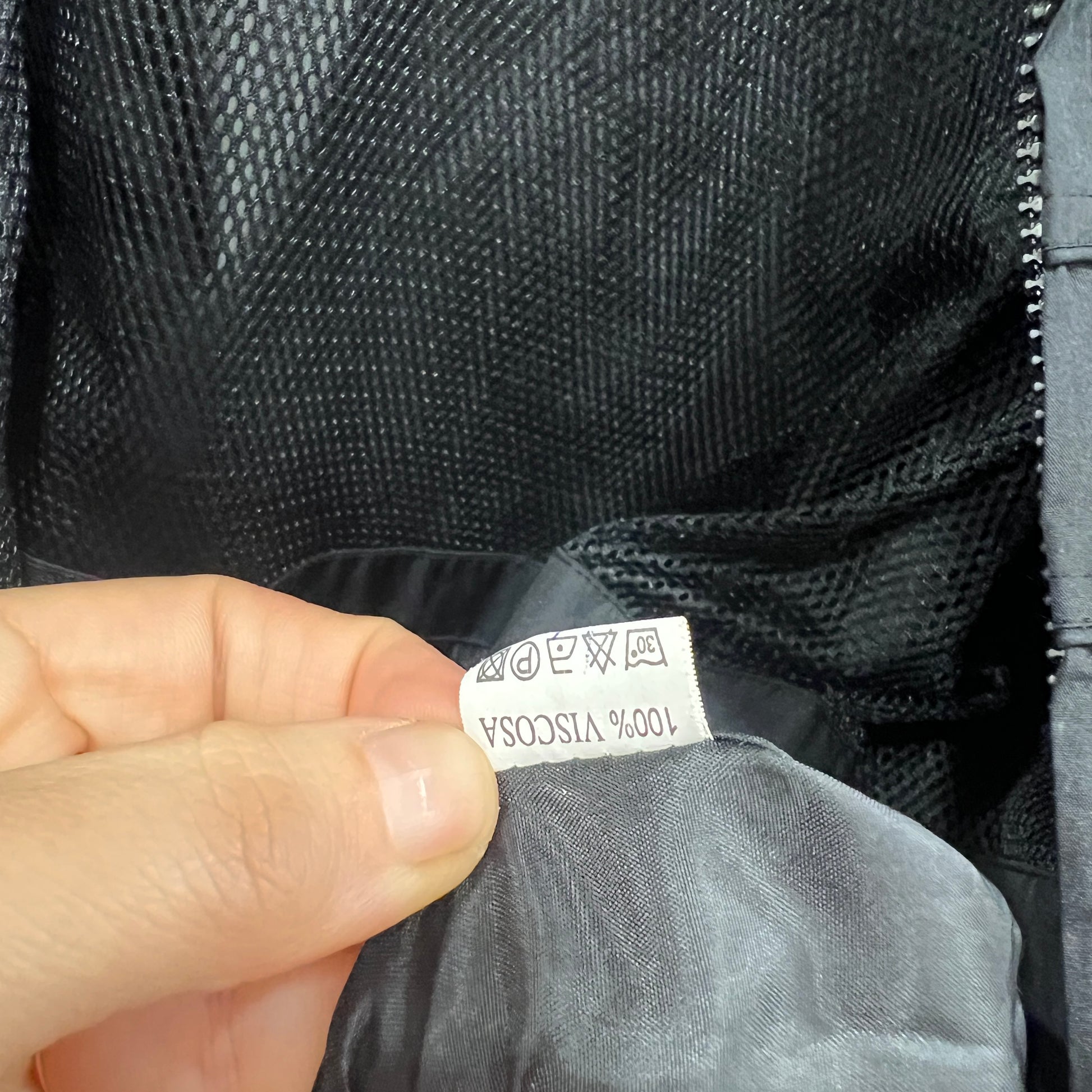 Hand holding a label on a black fabric garment with visible text