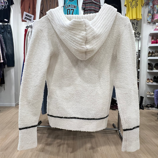 White hoodie with black trim on a rack in a store setting