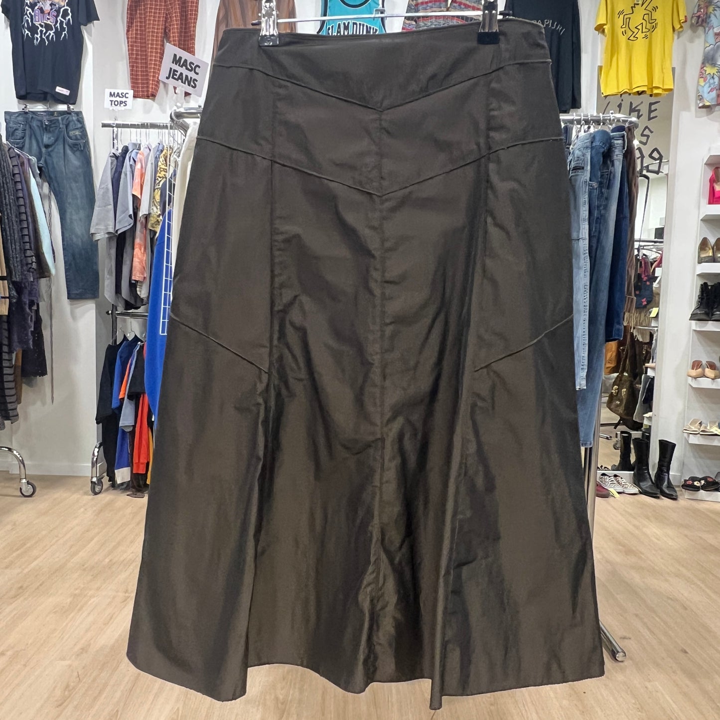 Dark skirt displayed in a clothing store with racks of clothes in the background