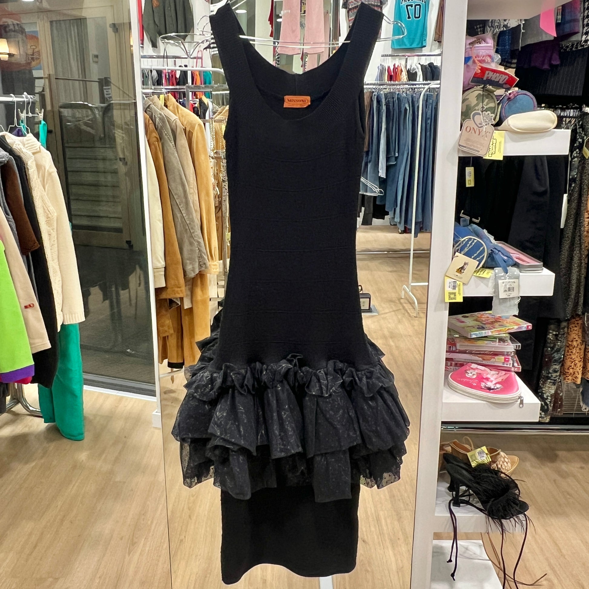 Black dress with ruffled layers on a rack in a store setting