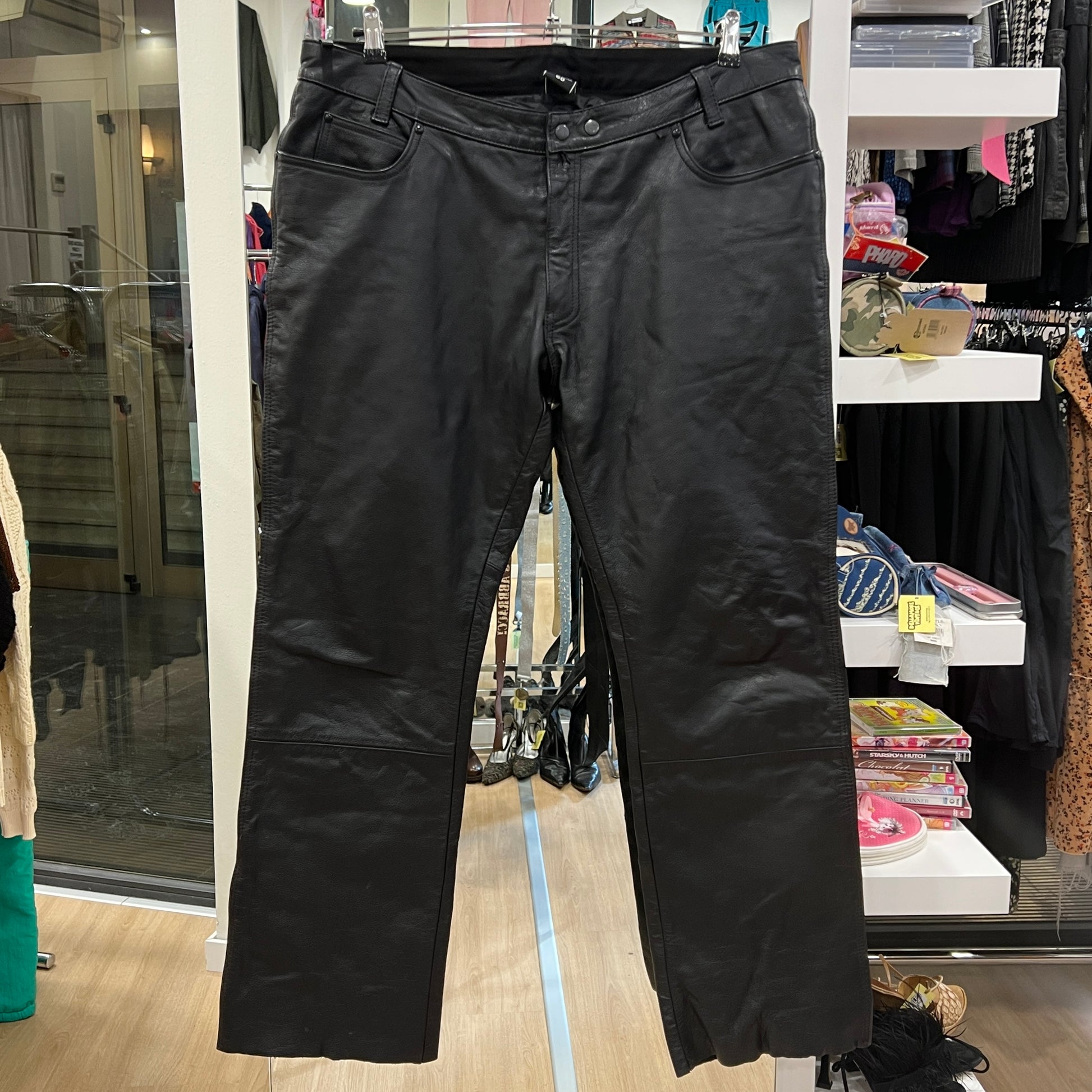 Black leather pants displayed in a store setting with various items in the background