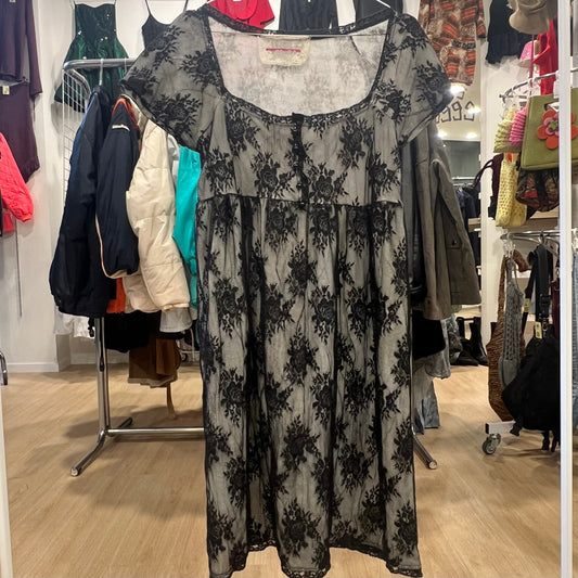 Black floral dress on a rack in a store setting with various clothing items