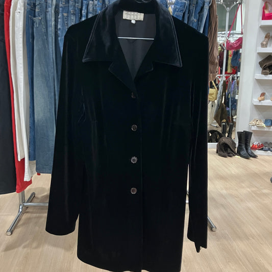 Black coat on a hanger in a clothing store with jeans and shoes in the background