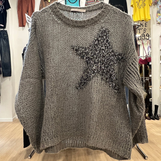 Gray sweater with a star design on a hanger in a store setting