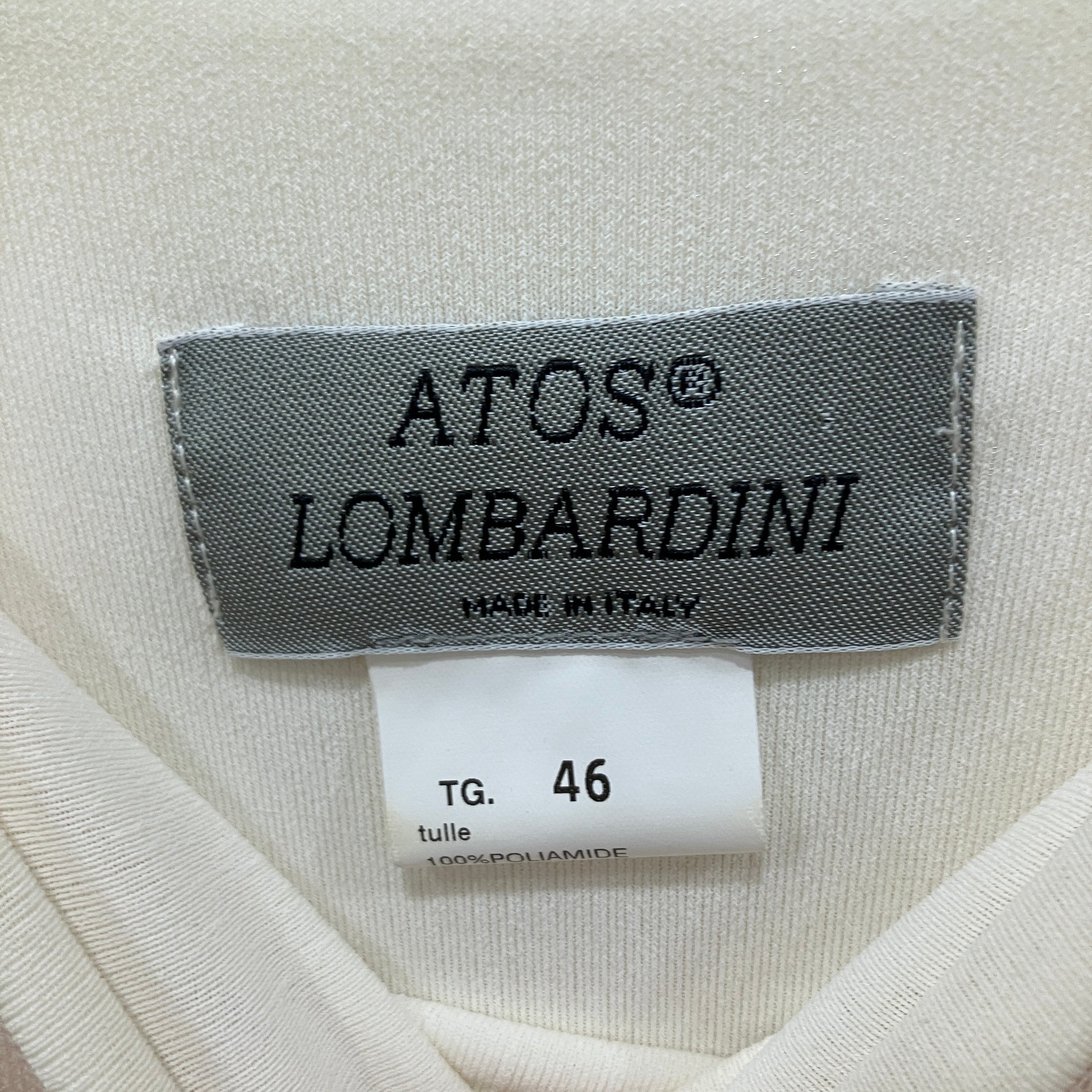 Label with 'ATOS LOMBARDINI' text on a fabric background