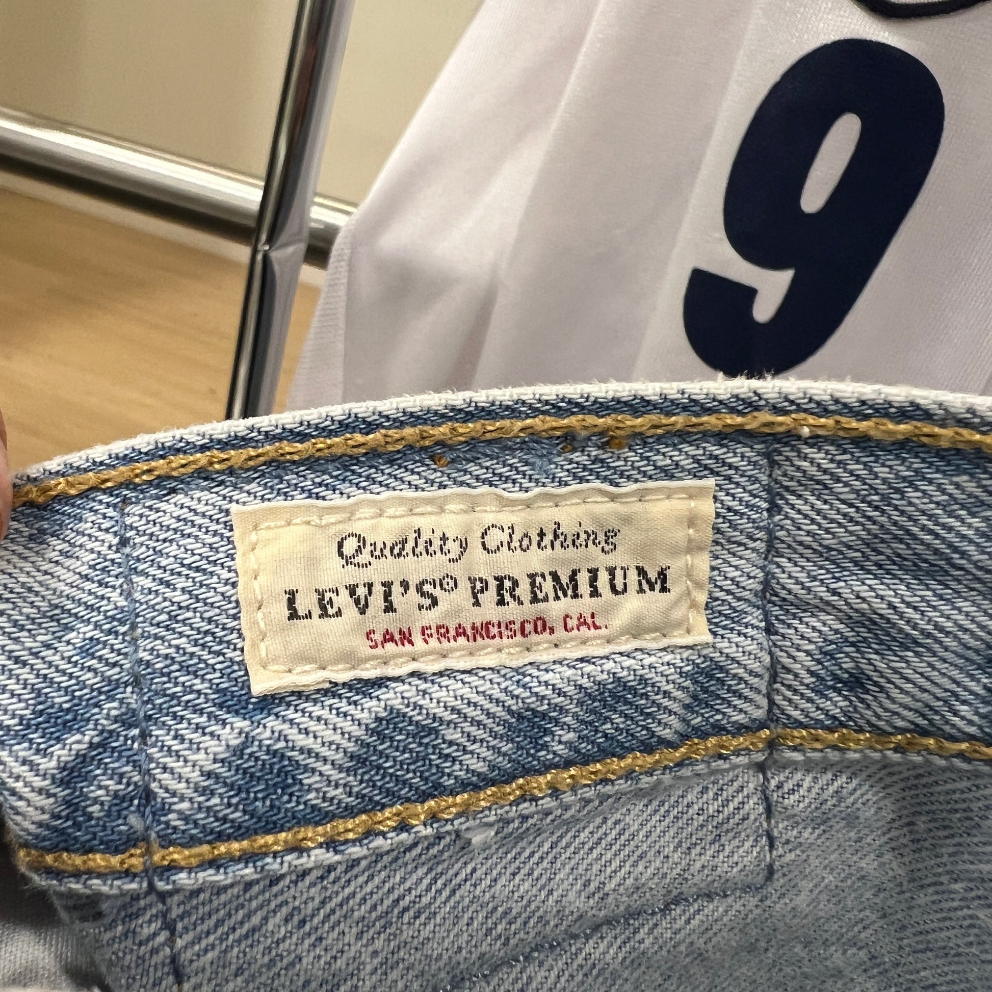 Close-up of a Levi’s Premium label sewn inside light-wash denim jeans, showing “Quality Clothing” text above the brand logo