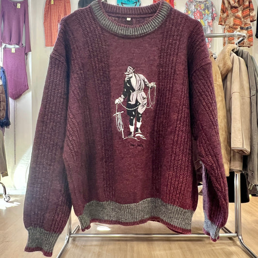 Maroon sweater with graphic design on a rack in a store setting