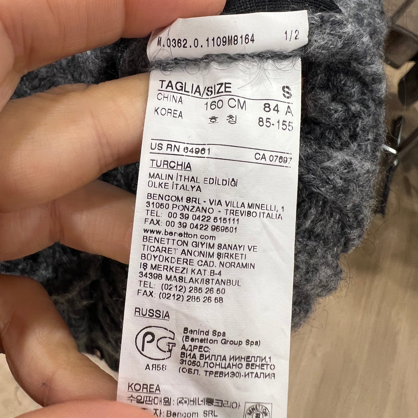 Clothing tag with size and brand information held by a hand