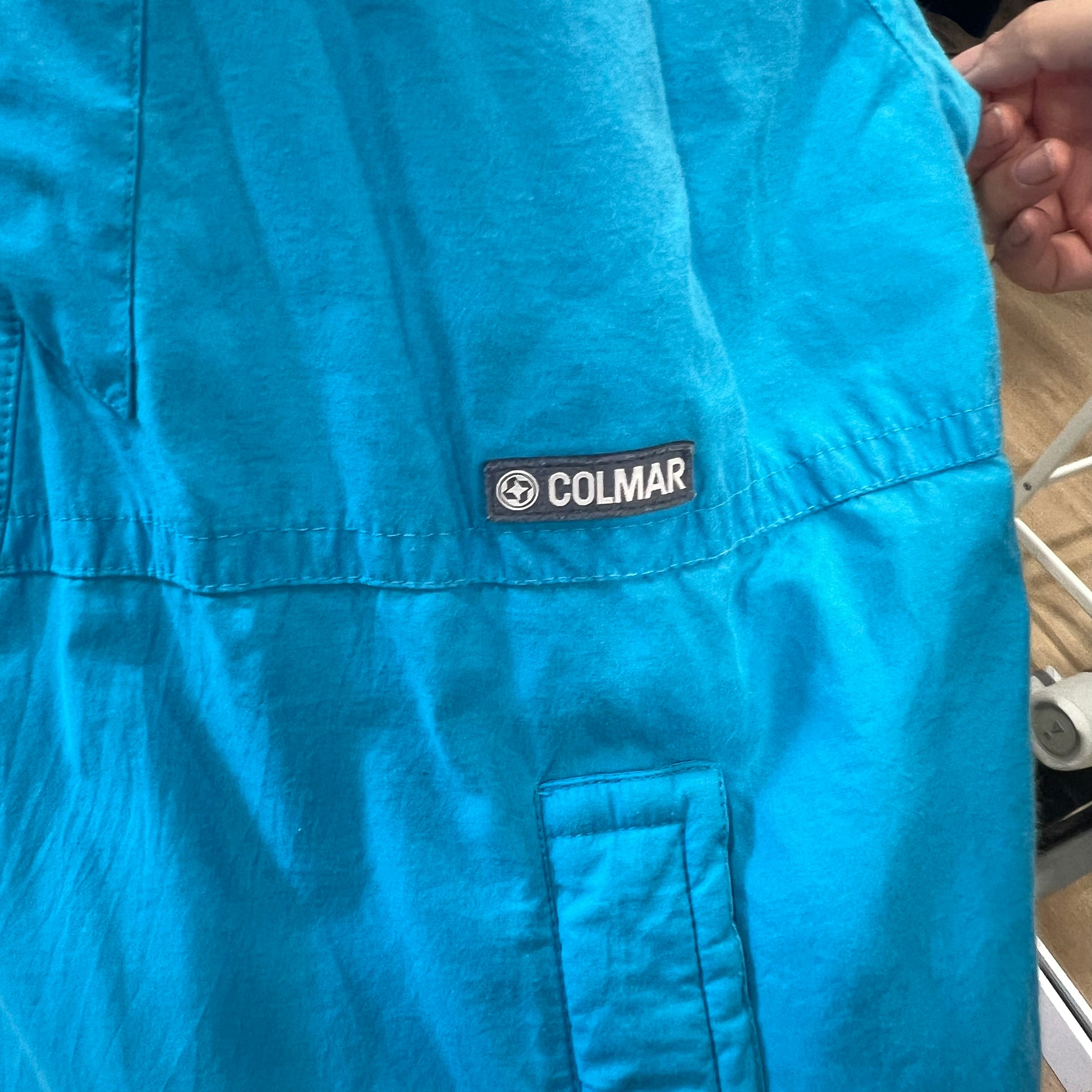 Blue shirt with Colmar logo on a blurred background