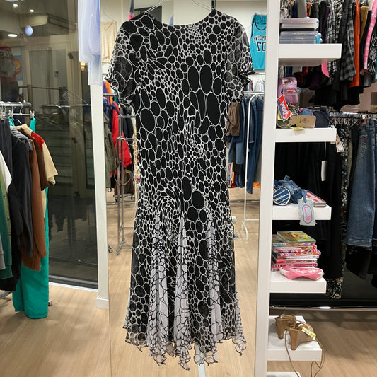 Black and white patterned dress on a mannequin in a store setting with racks of clothes and shelves in the background