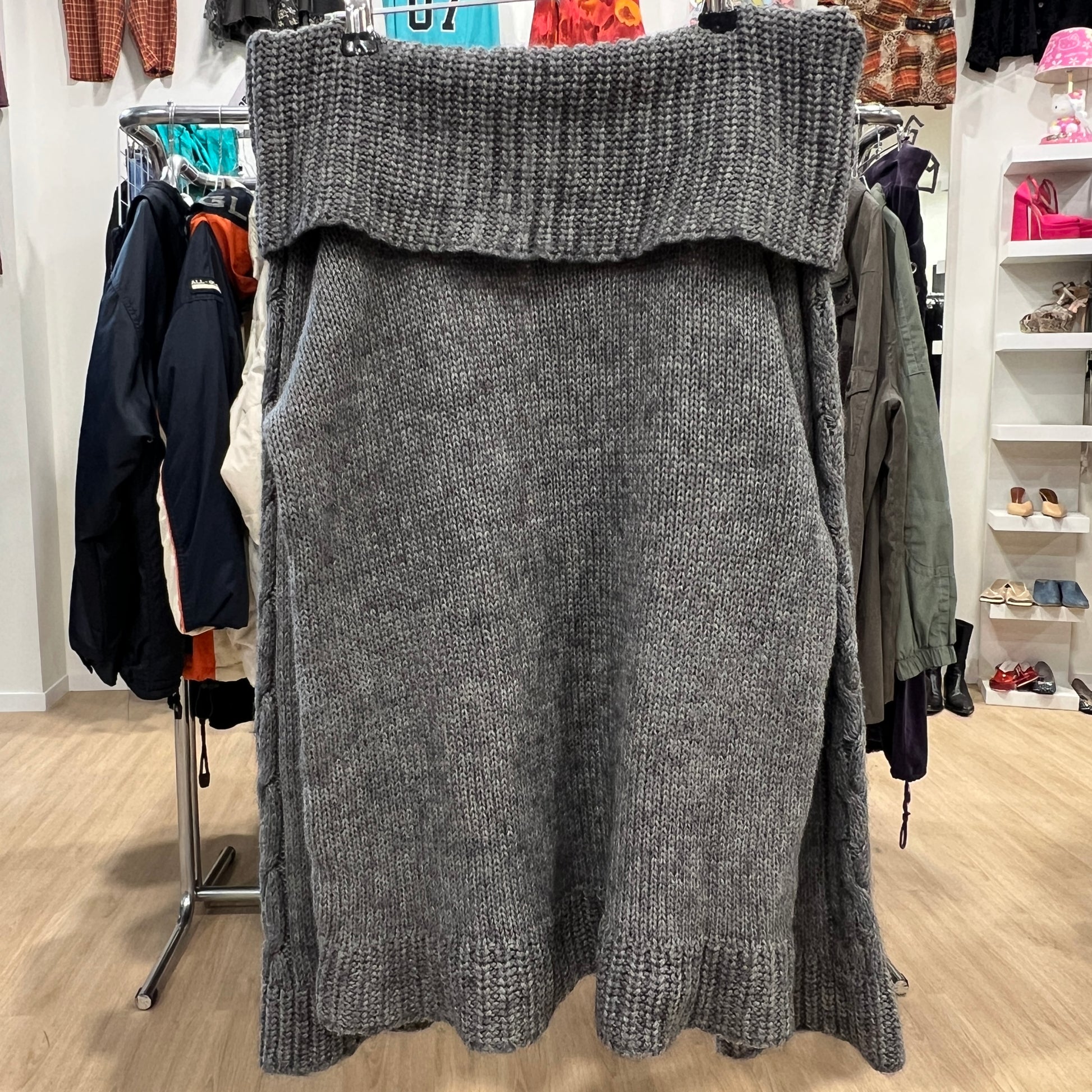 Gray knitted sweater on a hanger in a store setting