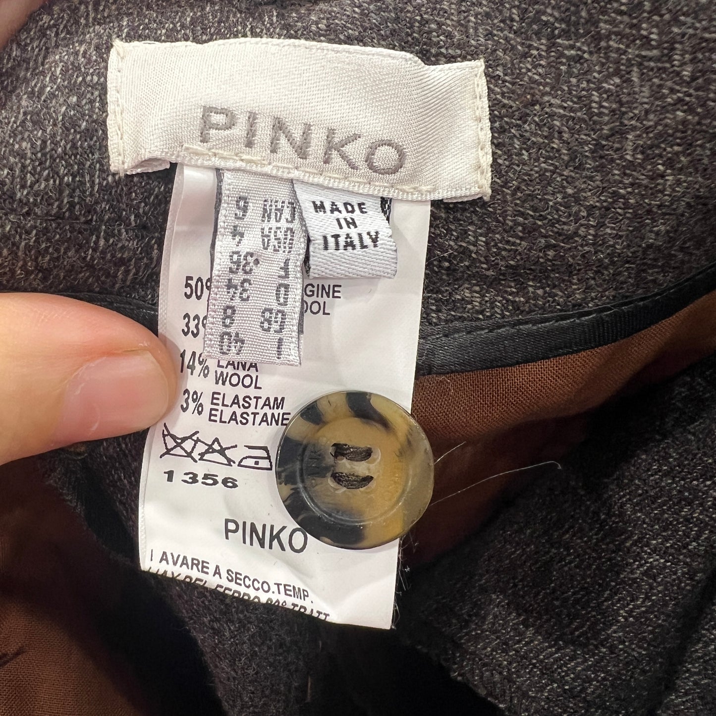 Close-up of a Pinko label on a garment with a button