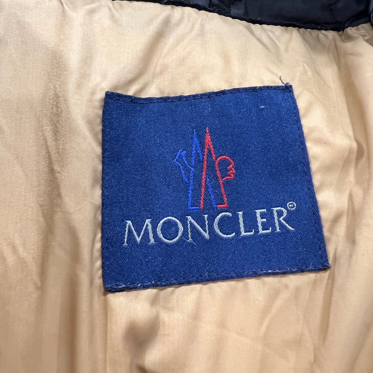 Moncler logo on a beige fabric background