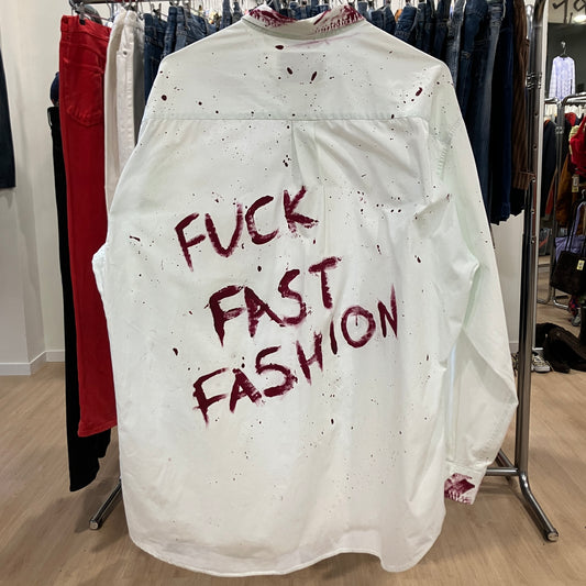 White shirt with red text 'FUCK FAST FASHION' on a rack in a clothing store
