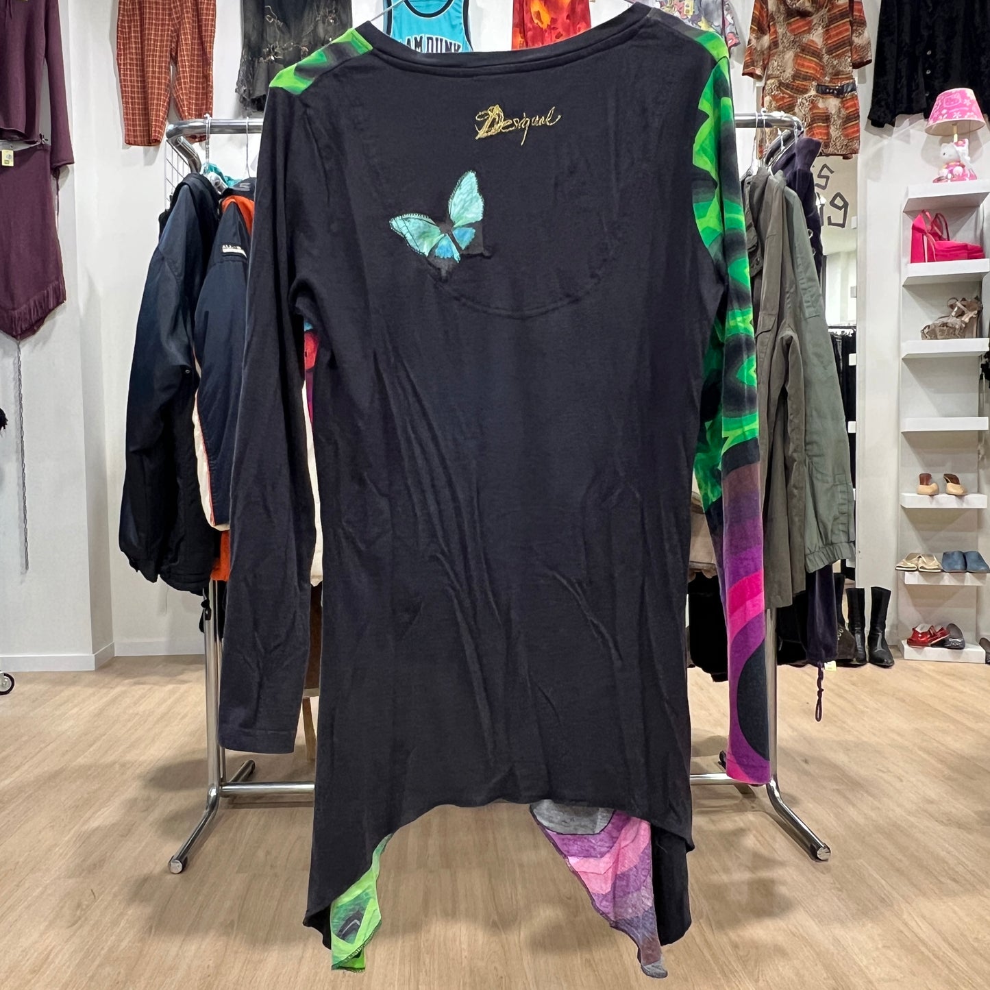 Black dress with a butterfly design on a clothing rack in a store