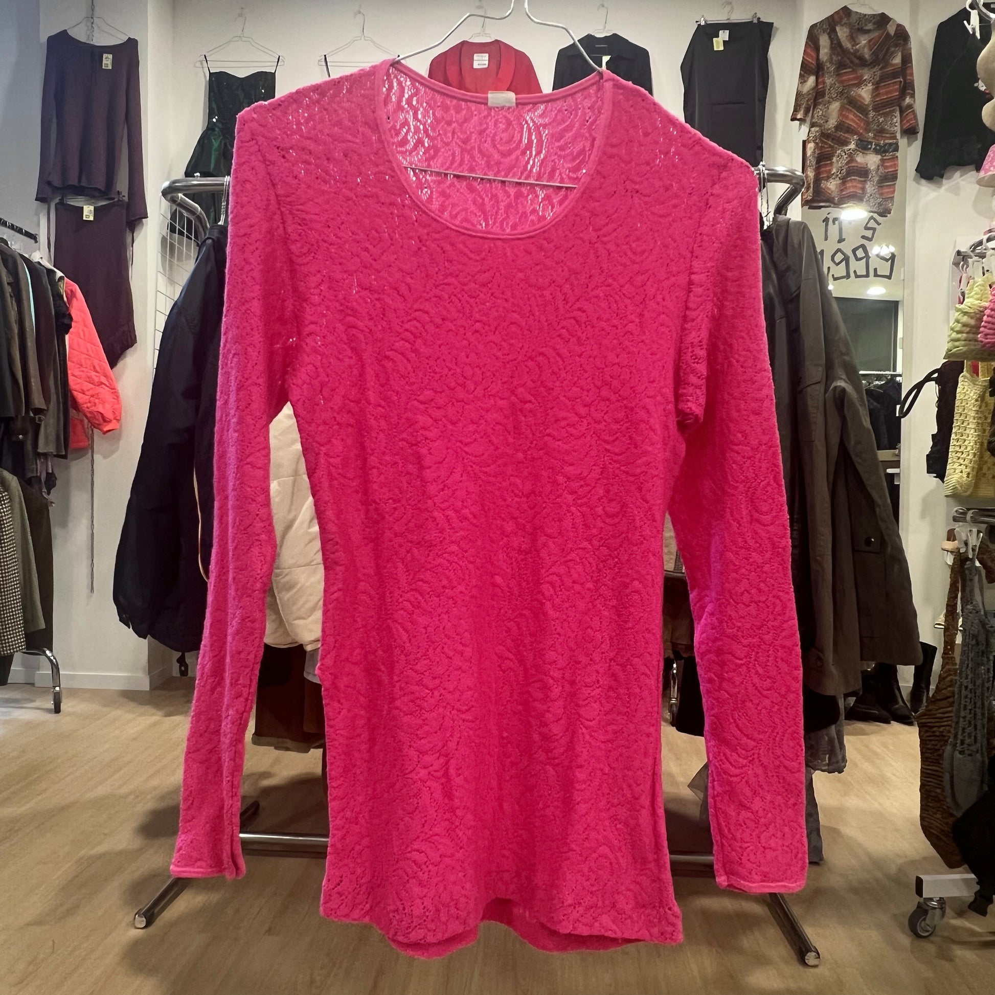 Pink long-sleeve top hanging on a rack in a clothing store