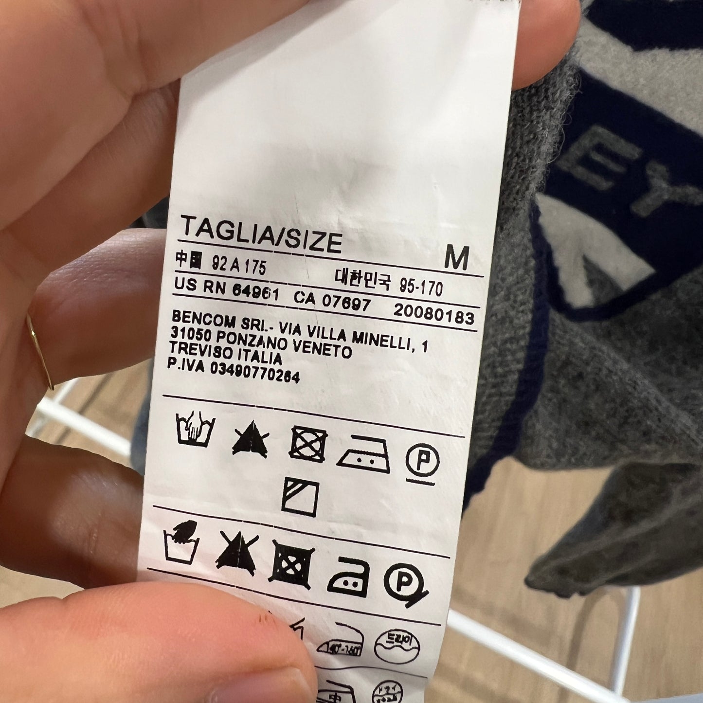Clothing label held by a hand with a blurred background
