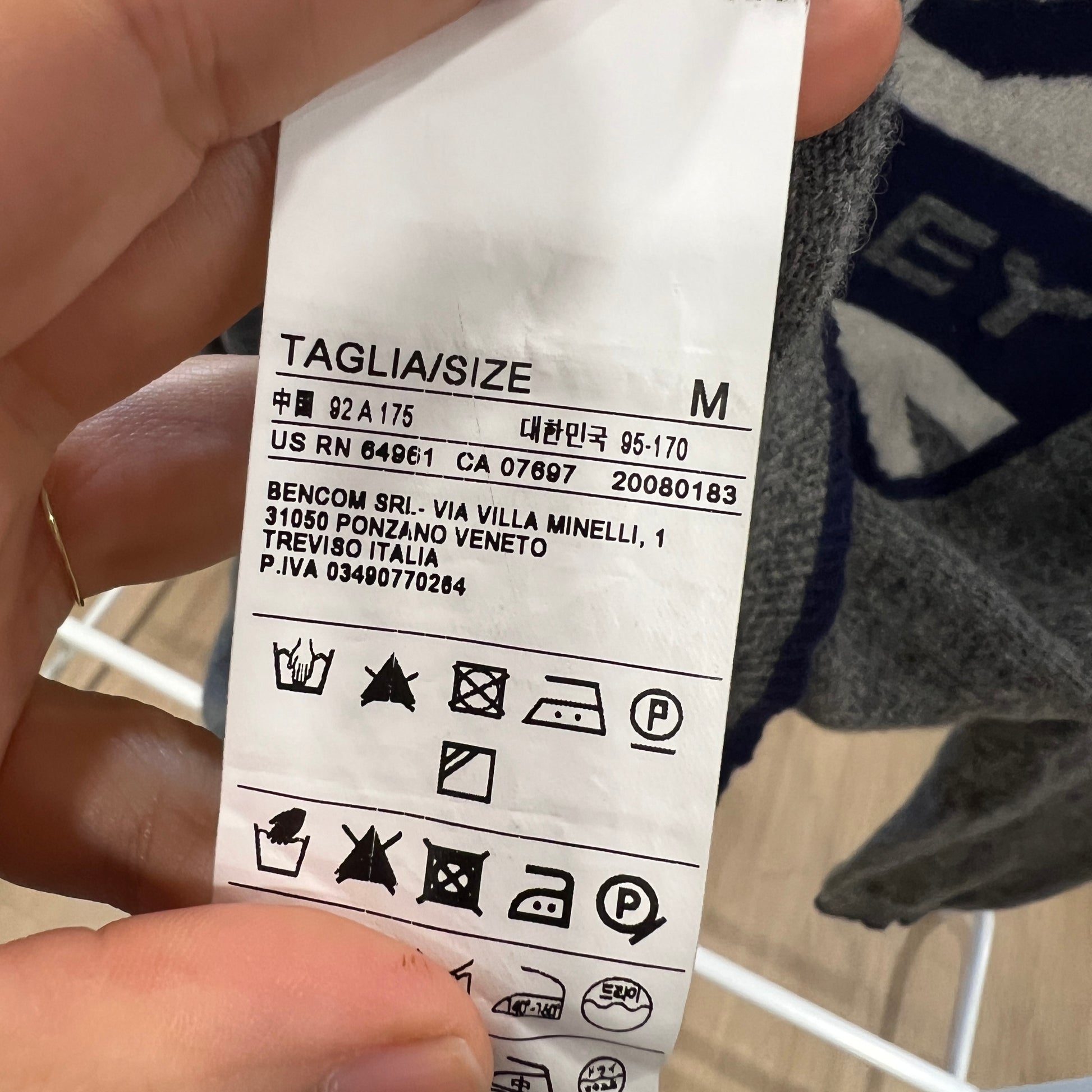 Clothing label held by a hand with a blurred background