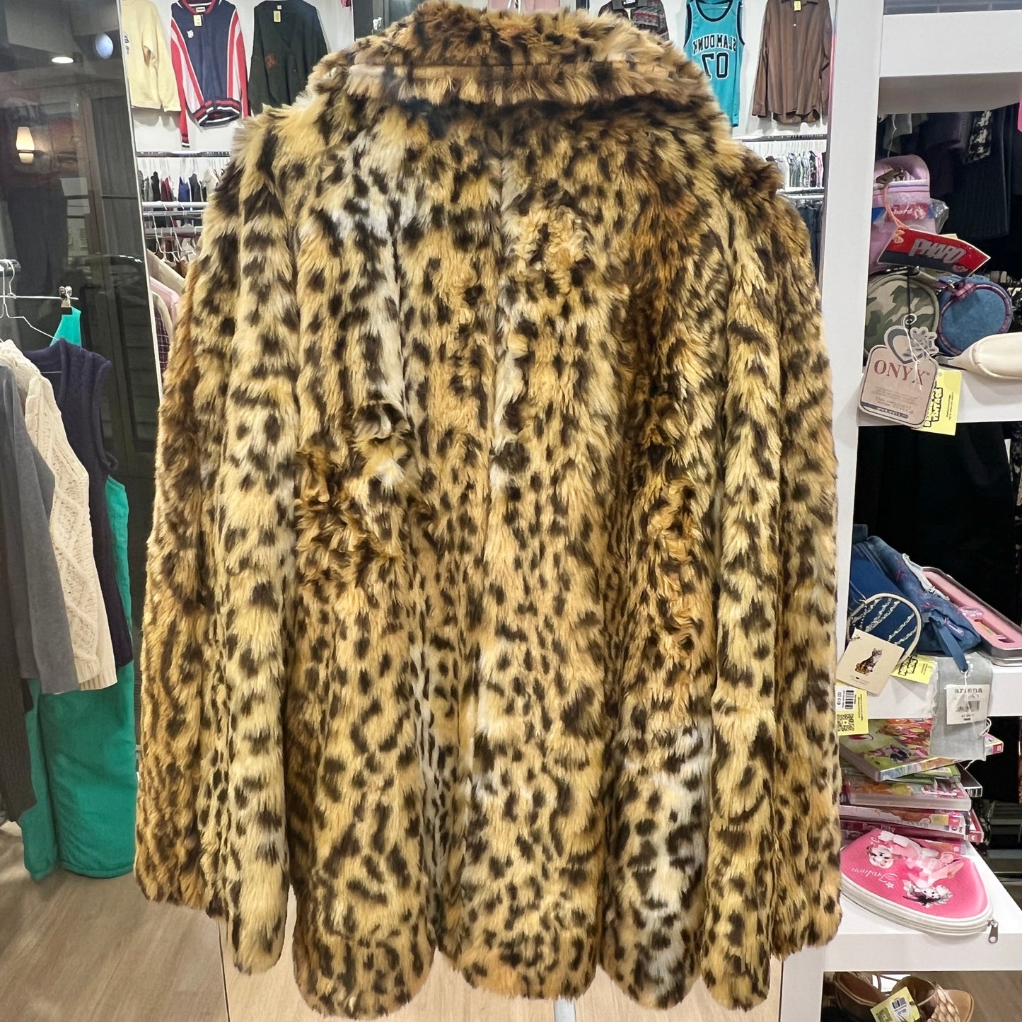 Leopard print coat in a store setting with clothing racks and shelves in the background