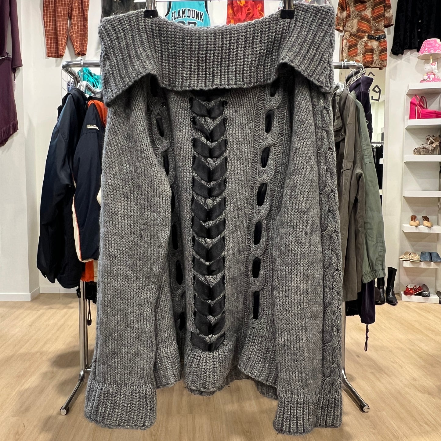 Gray knitted sweater with unique design on a clothing rack in a store