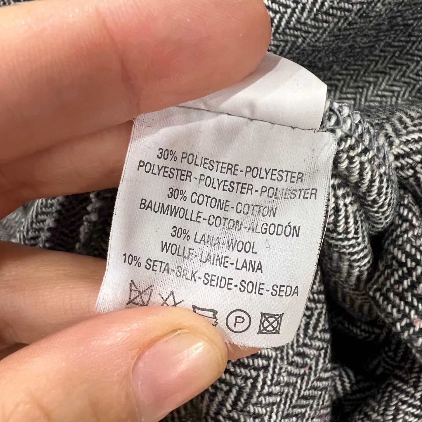 Clothing label with fabric composition details held by a hand against a textured fabric background