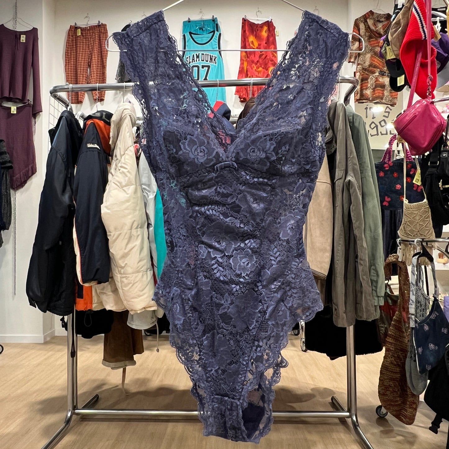 Blue lace dress on a rack with various clothing items in the background
