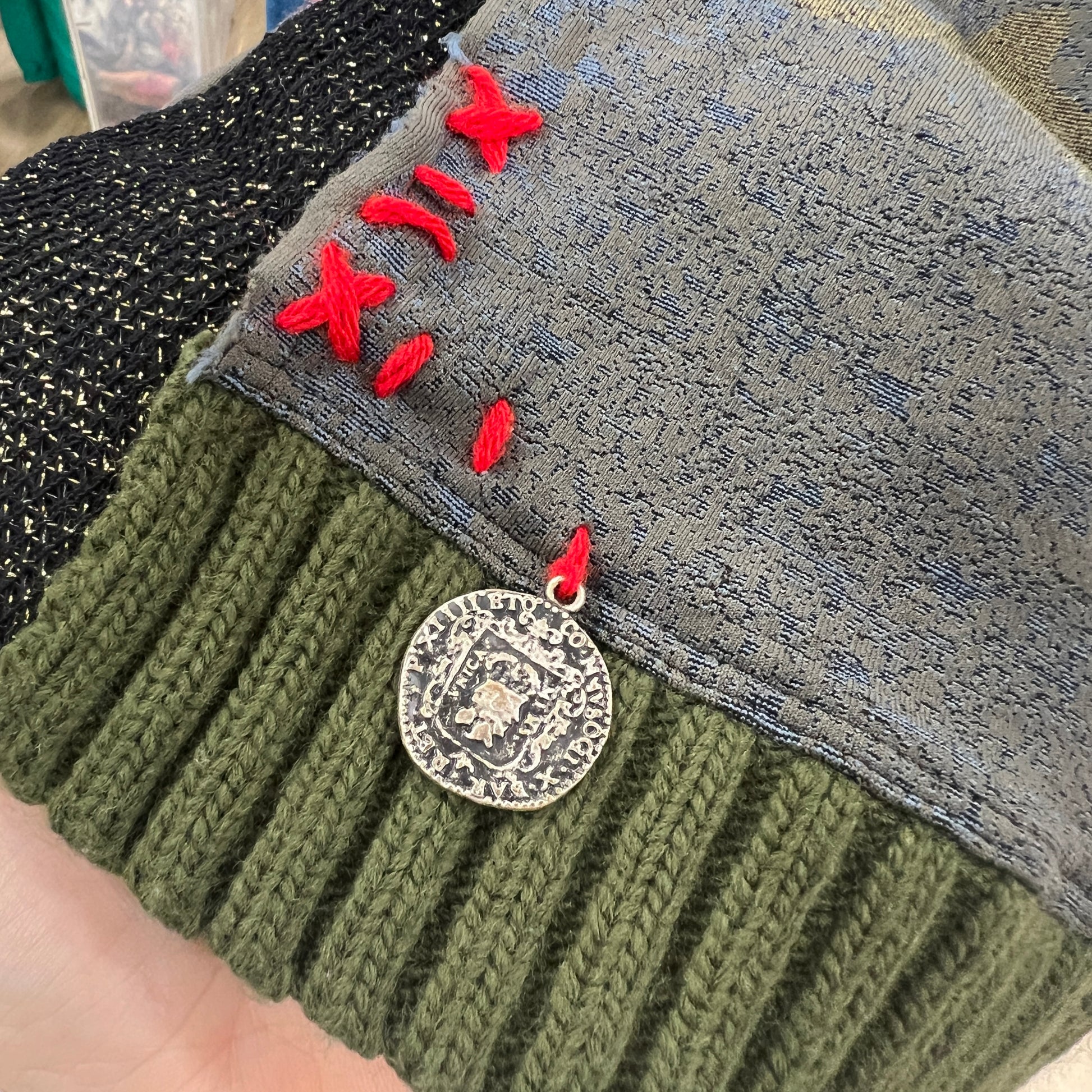 Close-up of a knitted fabric with red embroidered text and a metal badge