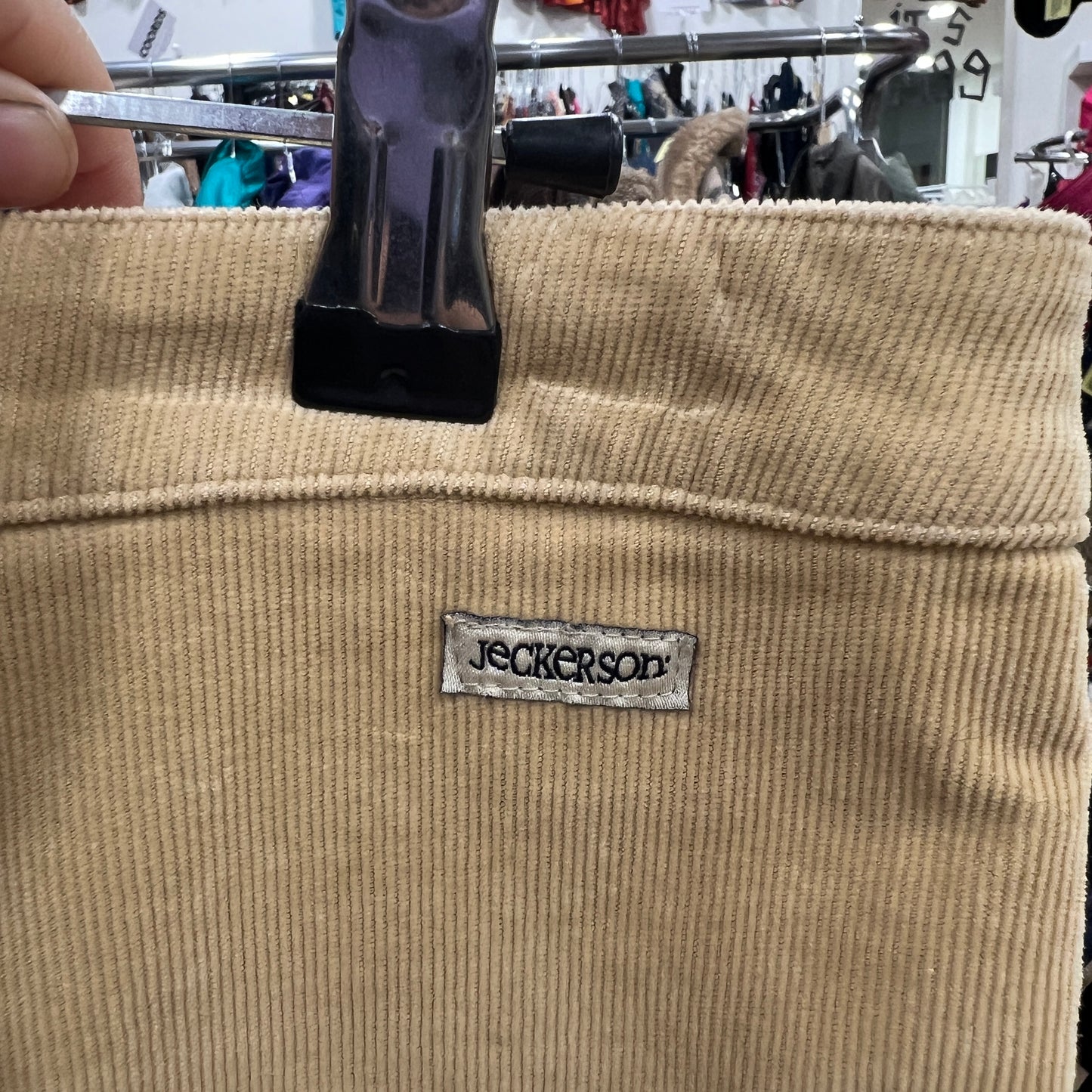 Beige corduroy pants with a label on a hanger in a store setting