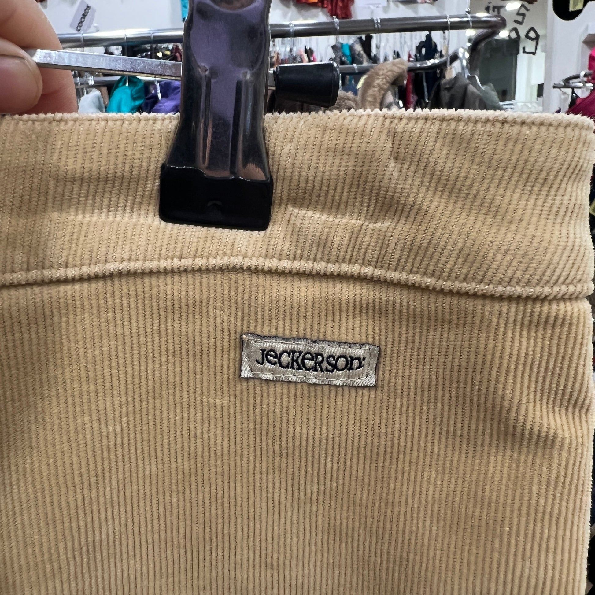 Beige corduroy pants with a label on a hanger in a store setting