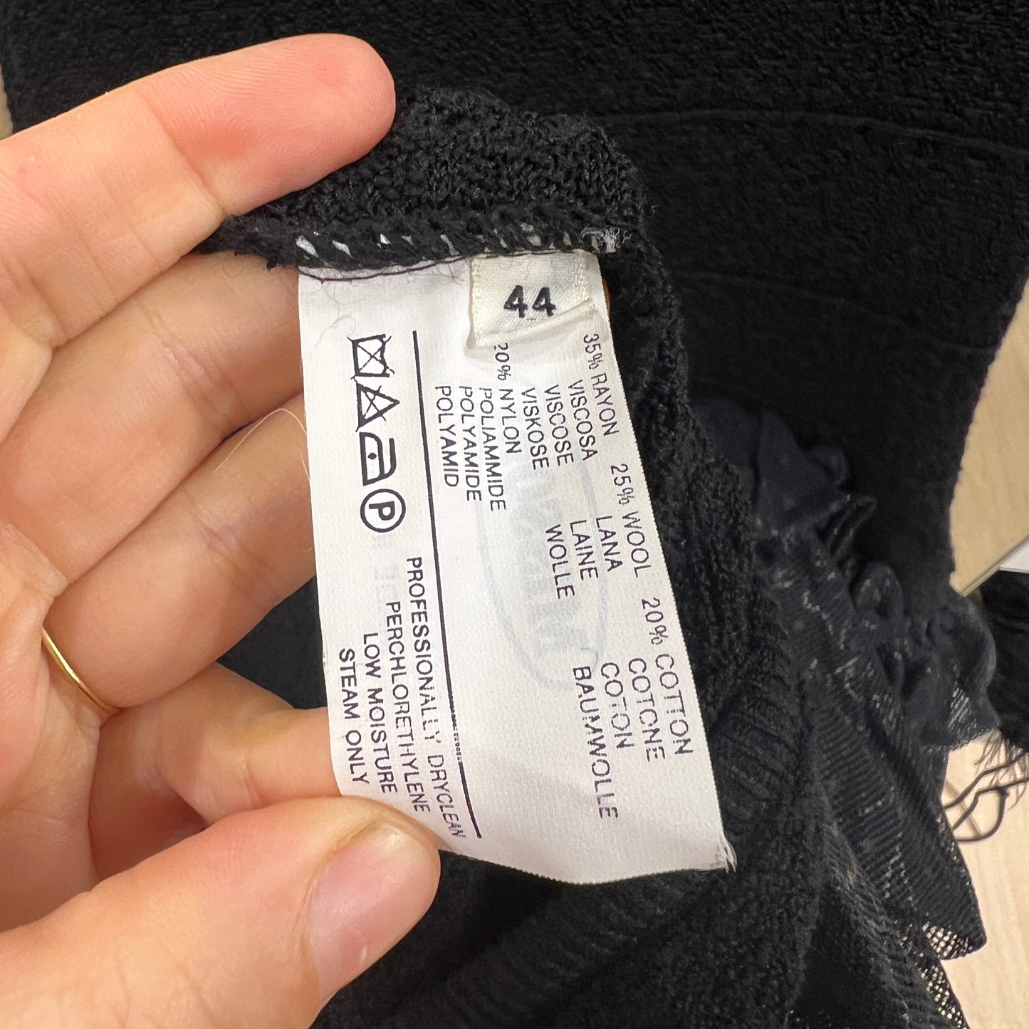Clothing label on a black garment held by a hand