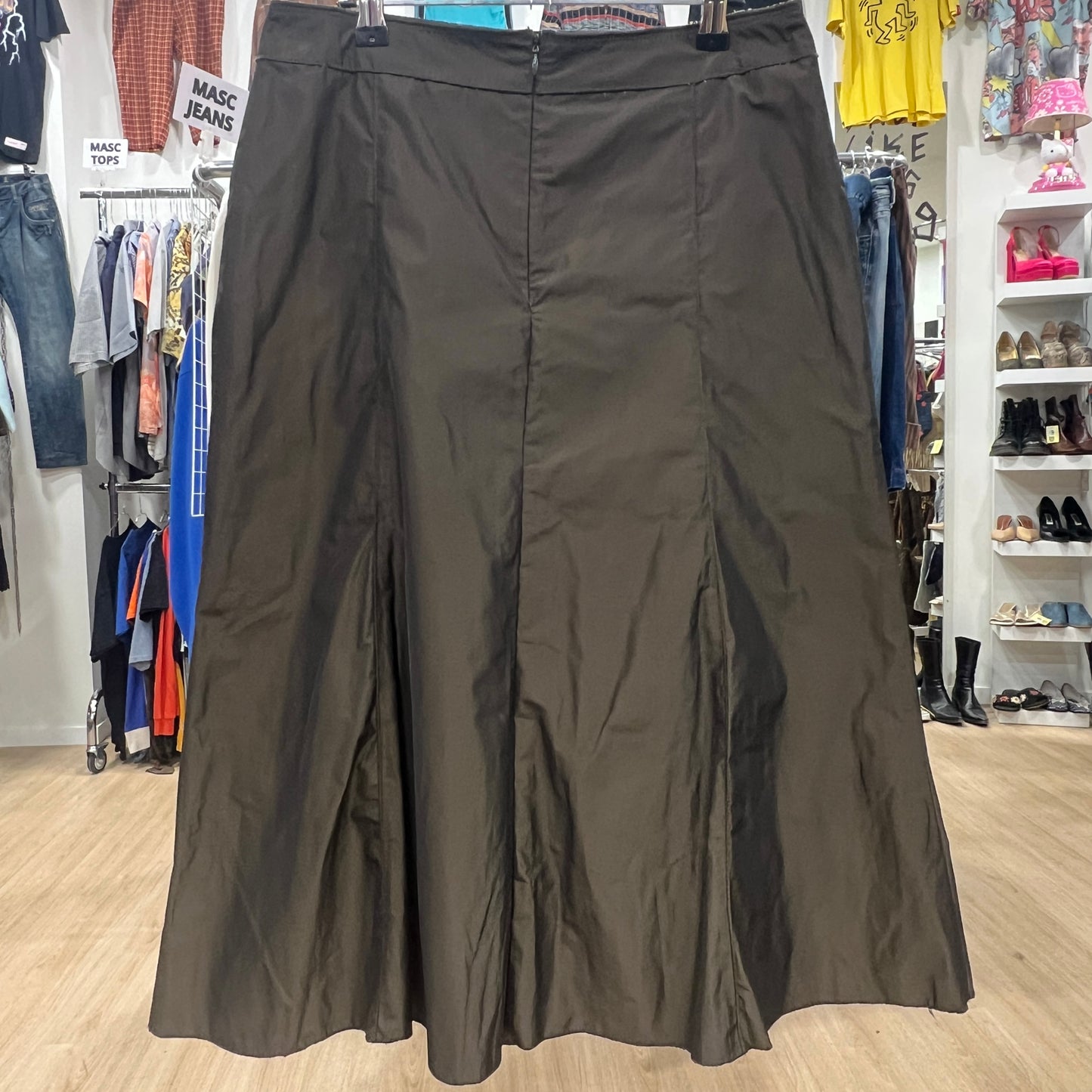 Dark green skirt displayed in a store with clothing and shoes in the background