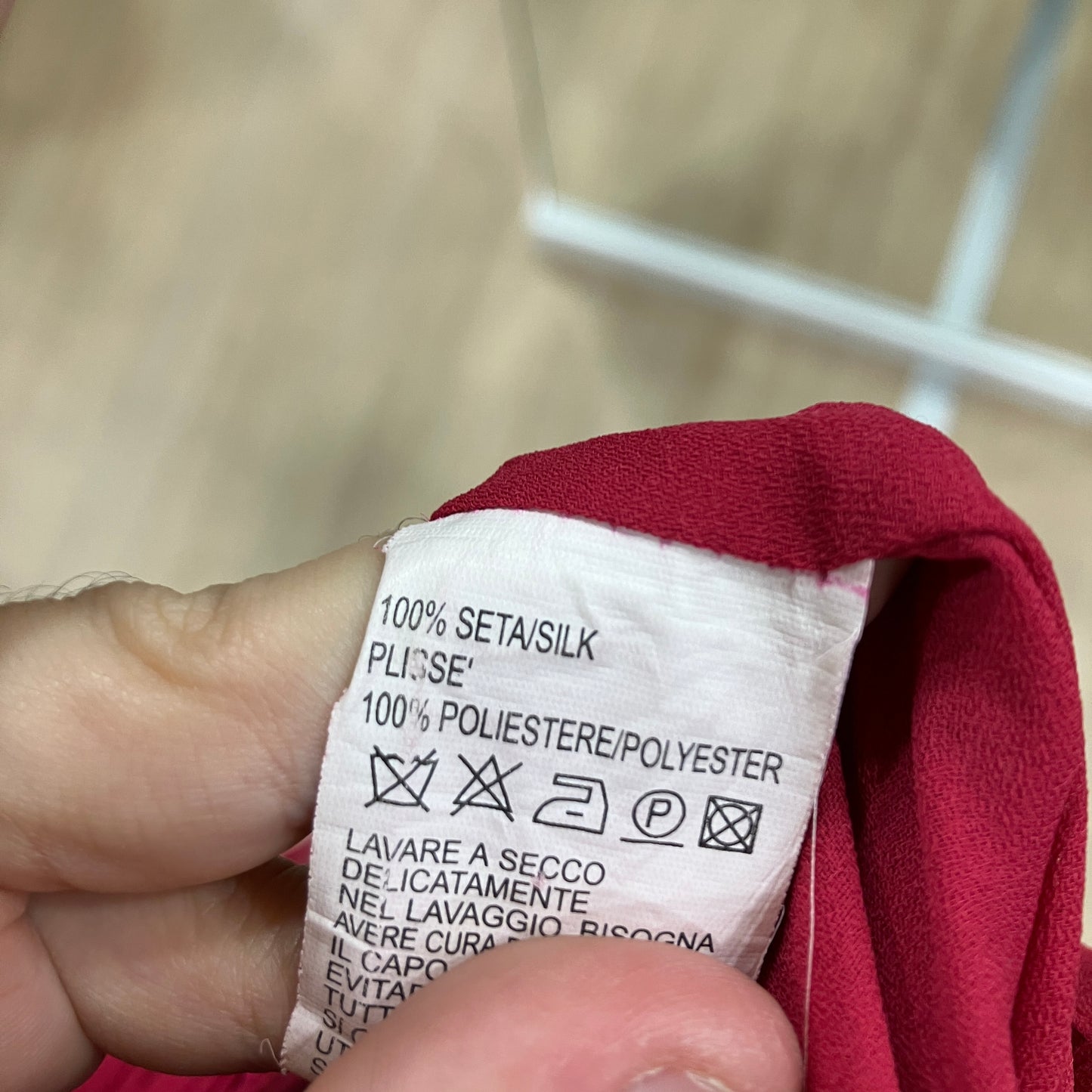 Clothing label on a red fabric with text and symbols