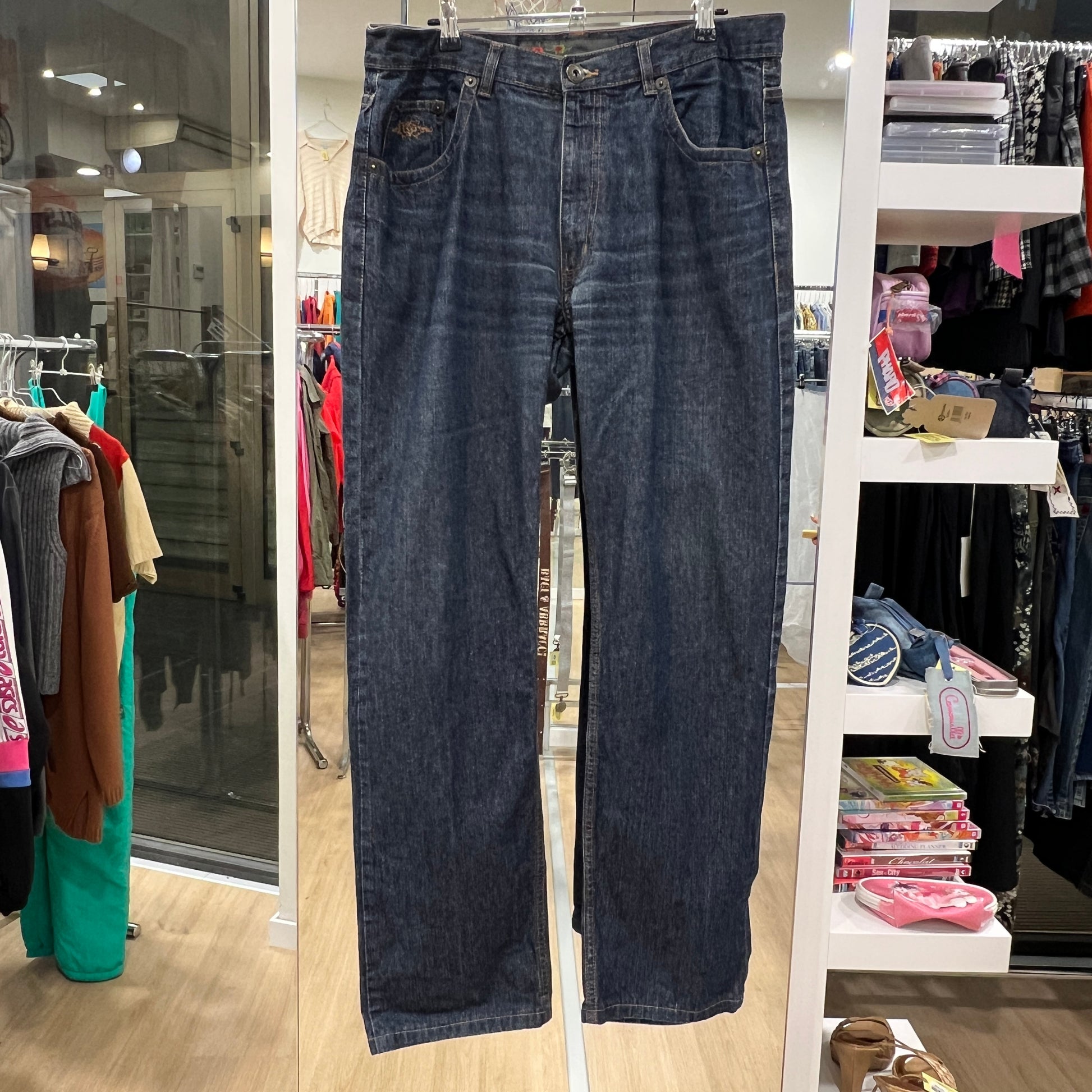Pair of blue jeans hanging in a store with clothing racks in the background