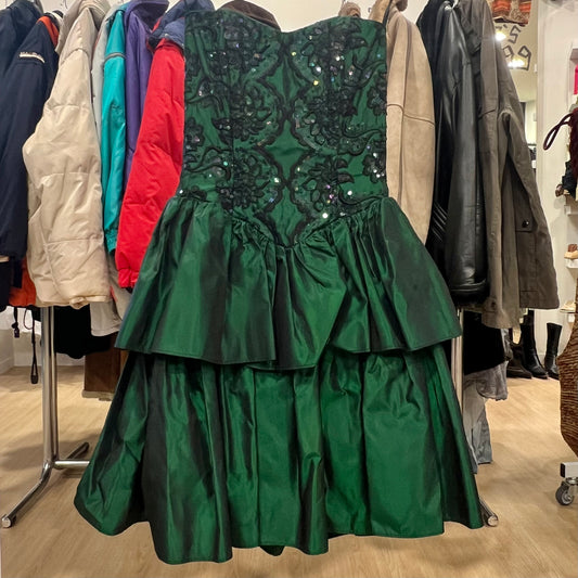 Green dress with sequin detailing on a rack of coats in a store