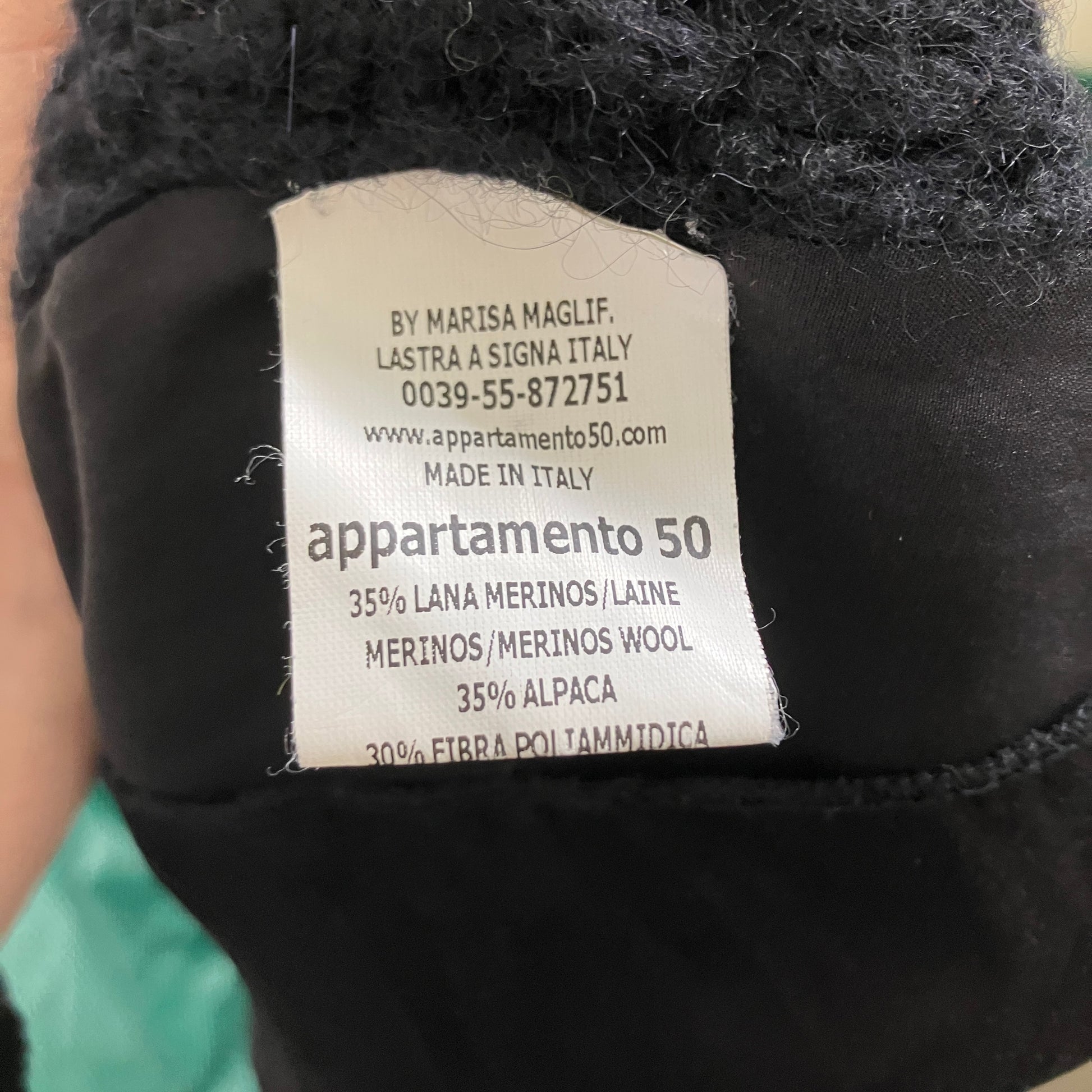 Label on a black garment with brand details and material information