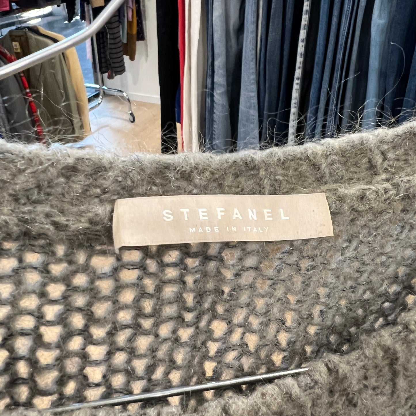 Stefanel label on a textured fabric with a clothing store background