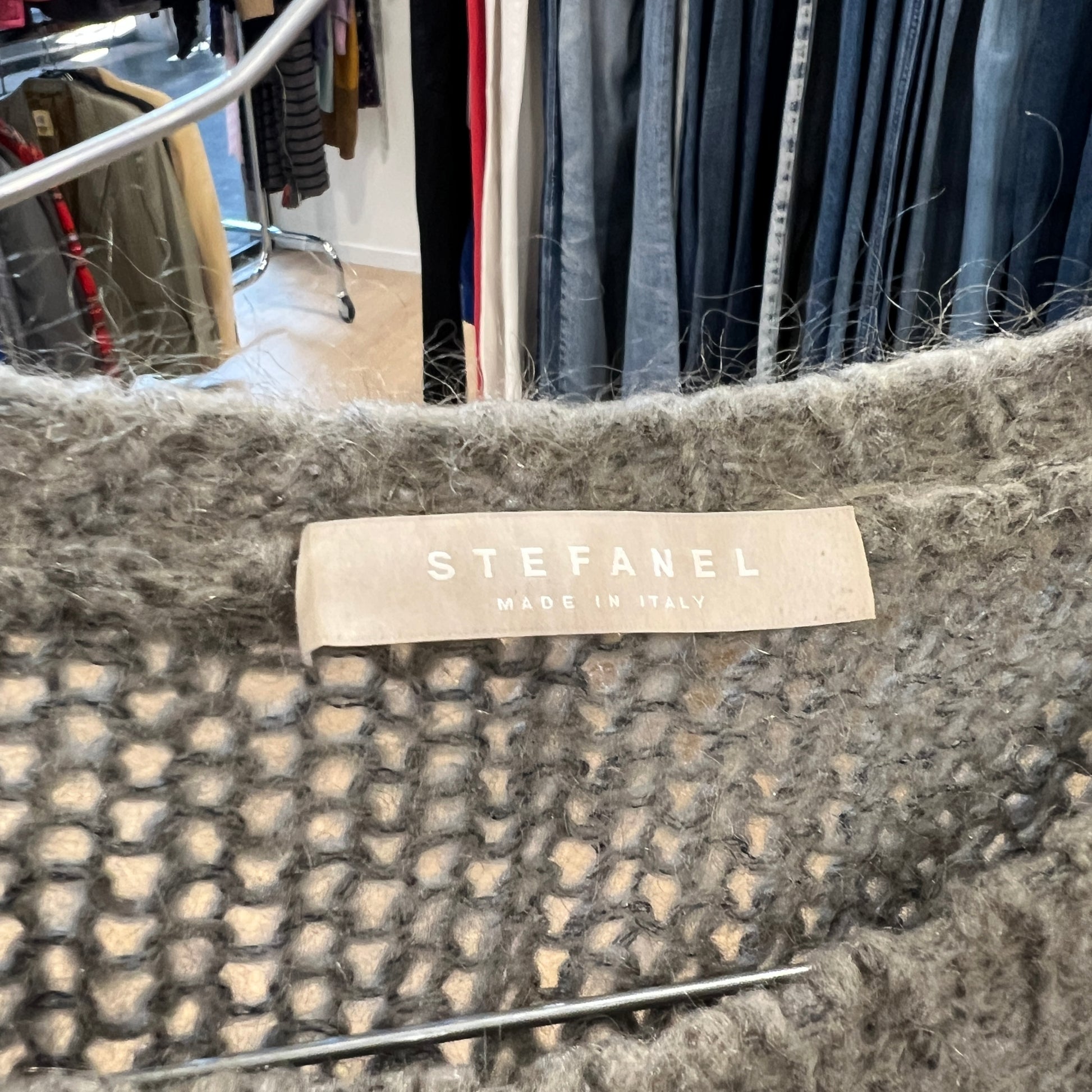 Stefanel label on a textured fabric with a clothing store background
