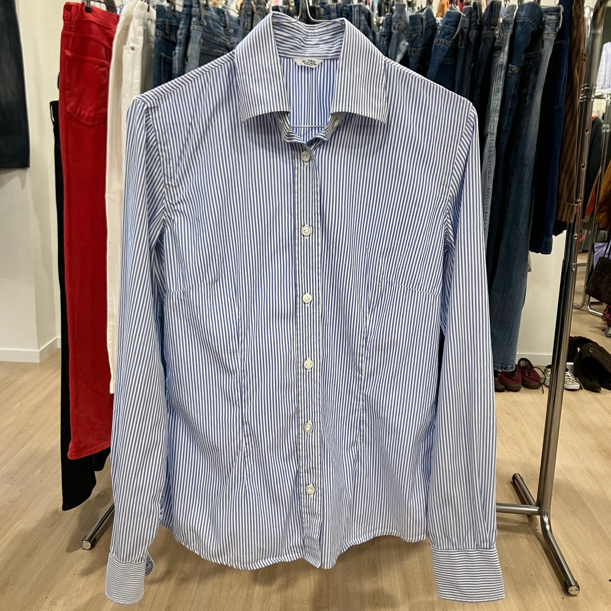 Blue and white striped shirt on a hanger in a clothing store