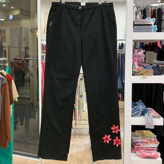 Black pants with floral embellishments hanging in a store setting