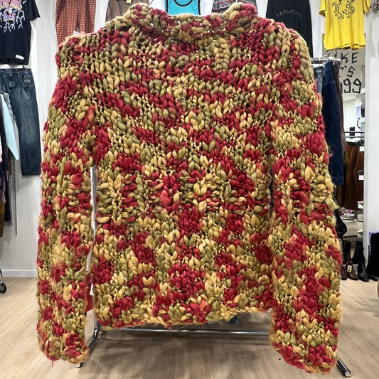 Multicolored knitted sweater on a rack in a store setting