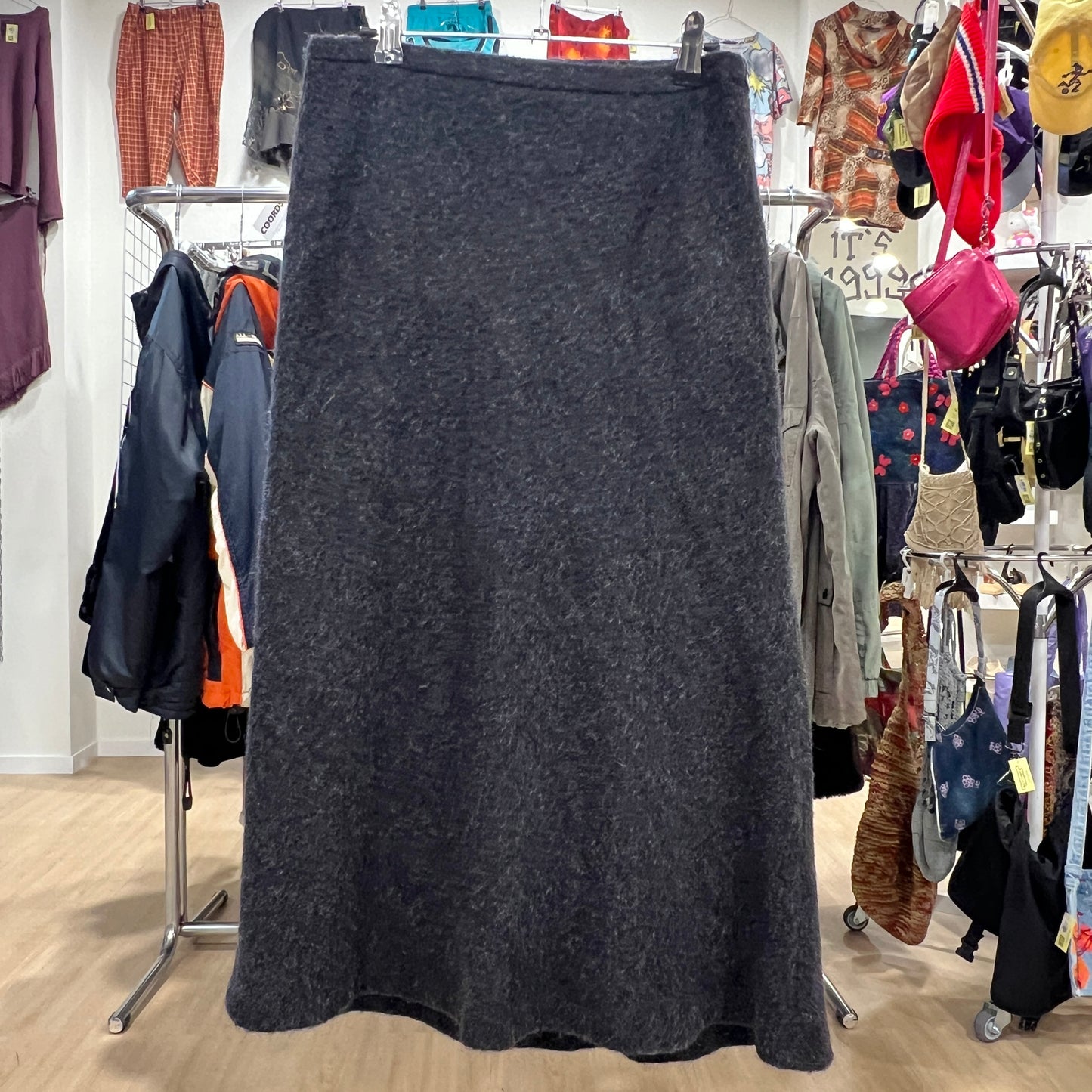 Dark gray skirt on a rack in a clothing store with various garments in the background