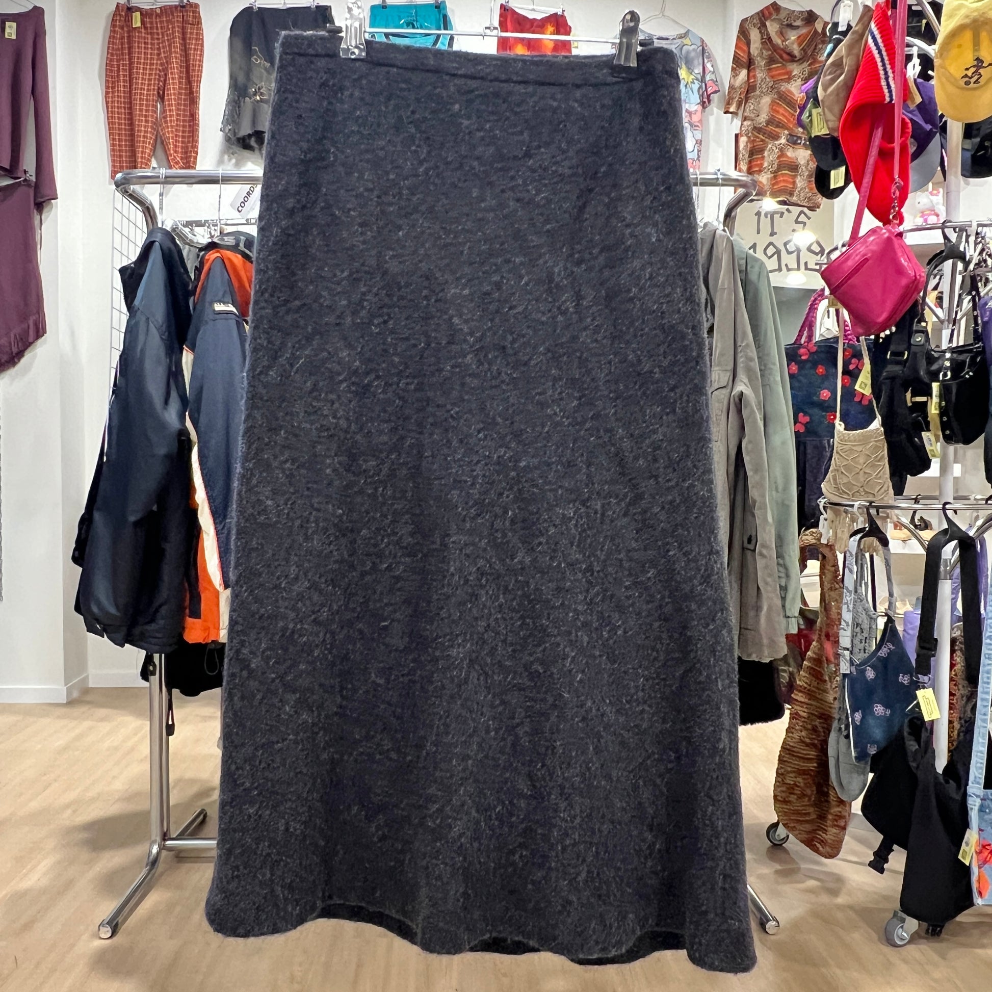 Dark gray skirt on a rack in a clothing store with various garments in the background