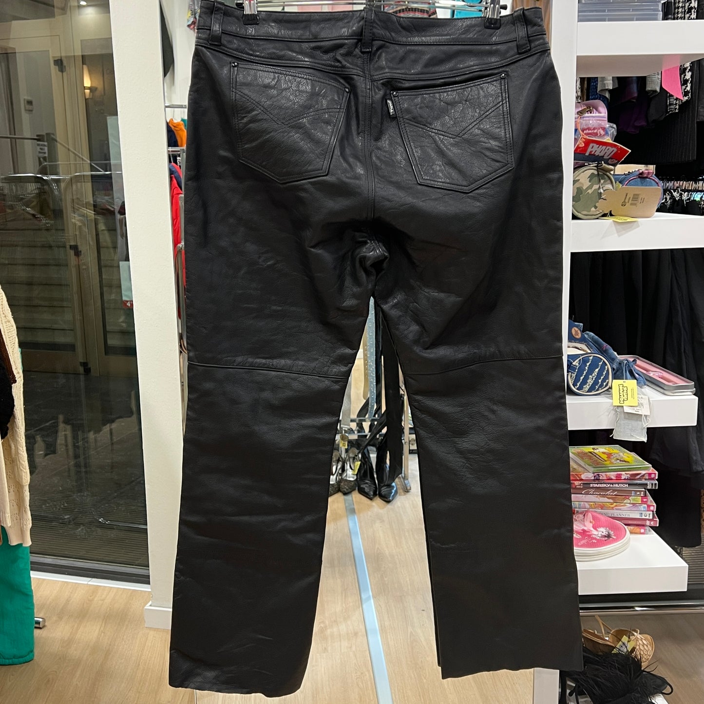 Black leather pants on a hanger in a store setting