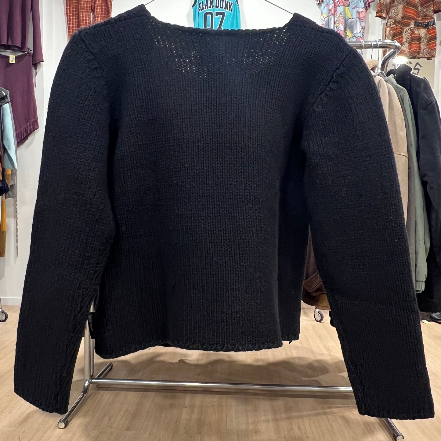 Black sweater on a clothing rack in a store setting
