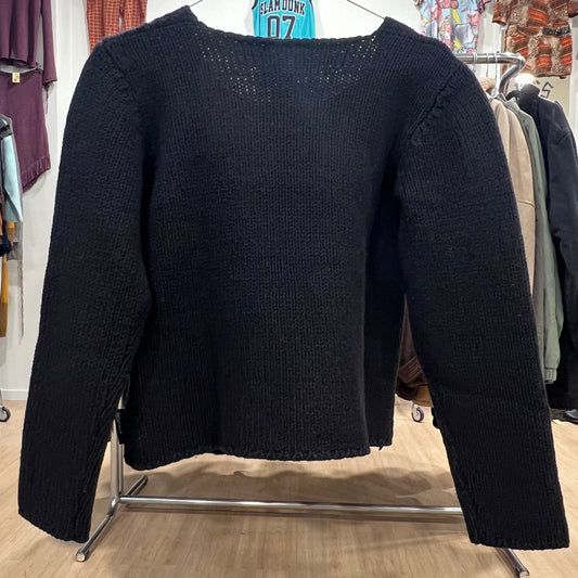 Black sweater on a clothing rack in a store setting