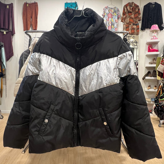 Black and silver puffer jacket in a store setting with other clothing items