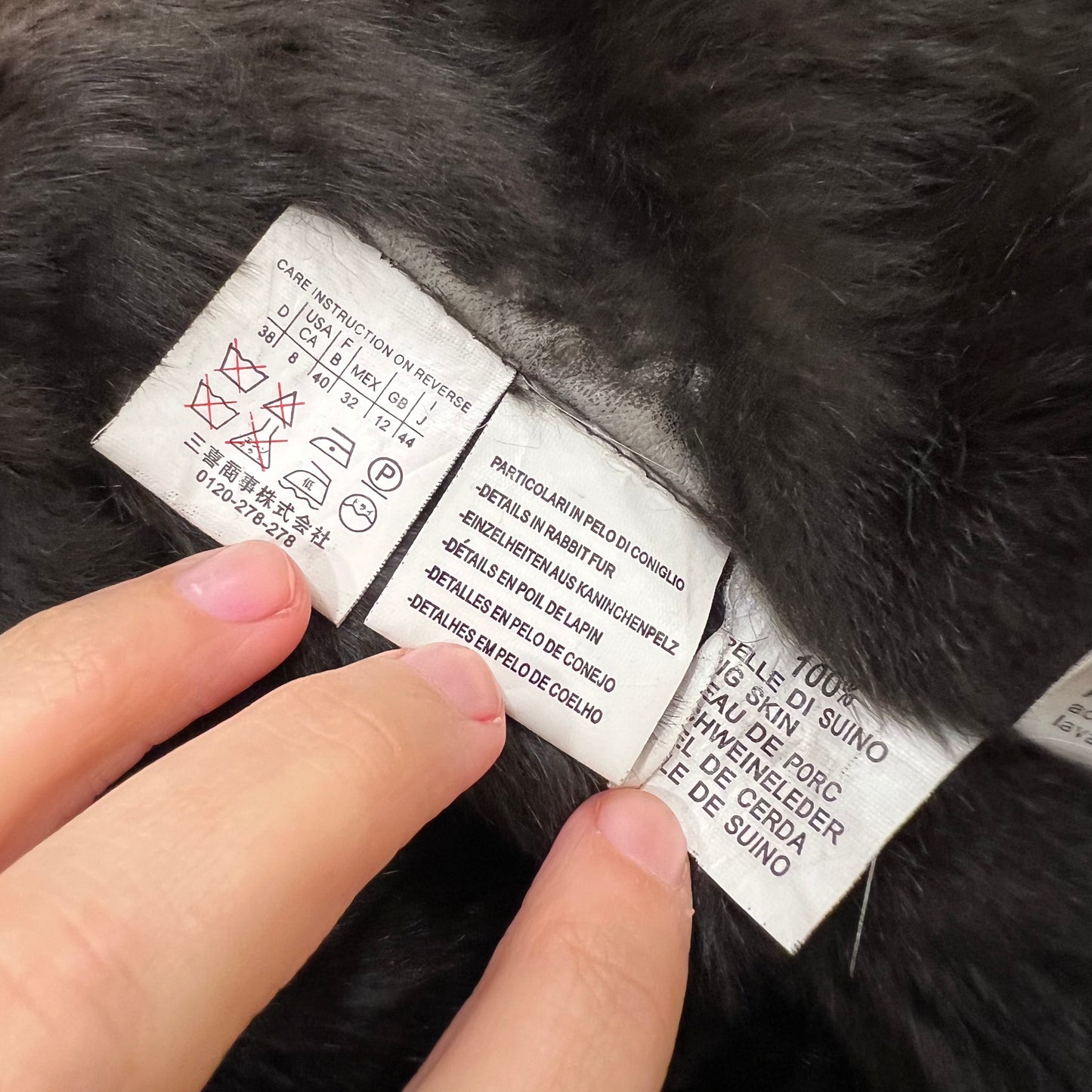 Close-up of a fur product with labels and a hand pointing to them