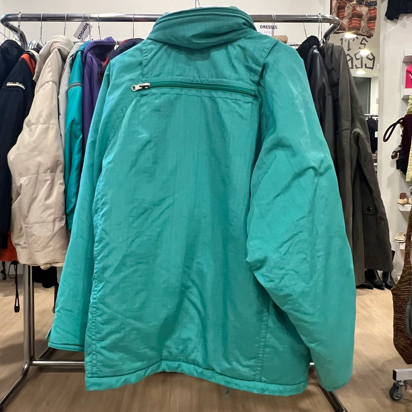 Teal jacket hanging on a rack in a store setting